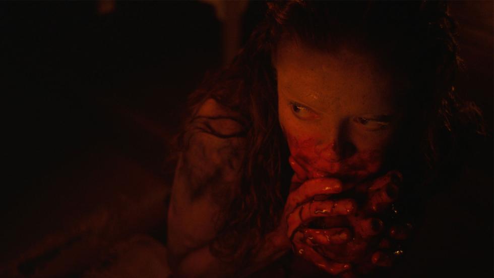 A woman with bloodied hands hides