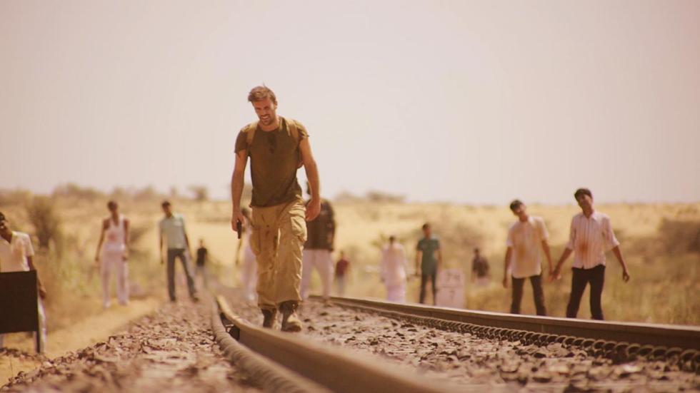 The Dead 2, India! man walks on railroad tracks with zombies in the background