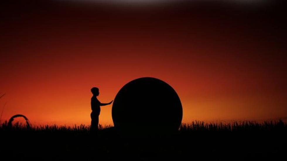 The Landing man touches circular object in a field