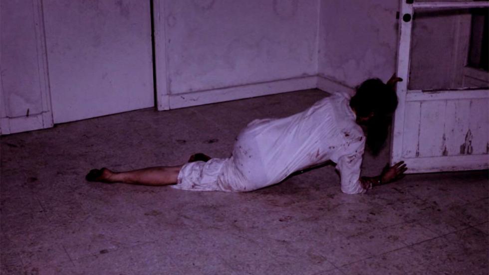 Therapy film still woman crawls to the door.