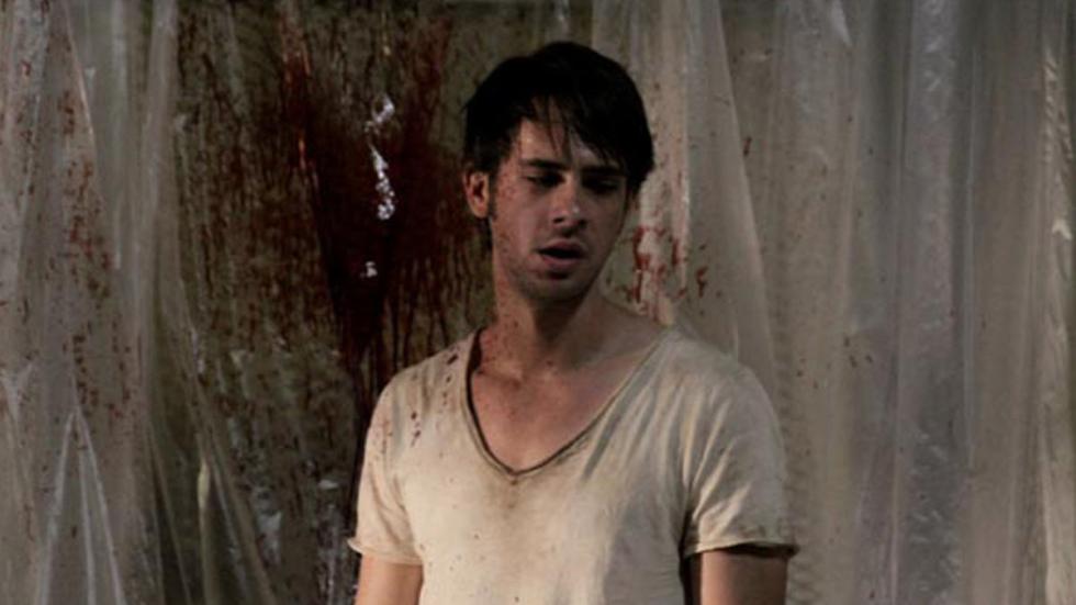 Undocumented man stands in front of a bloodied curtain