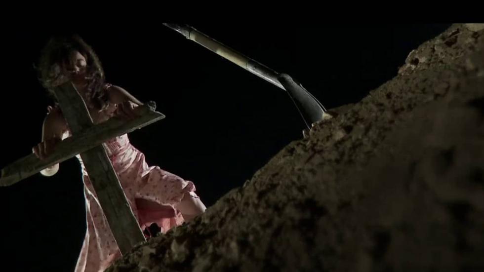 Y VOLVERÃ man pushed a cross down near newly dug grave